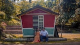 A couple sharing a warm moment on the porch of their rent-to-own house with lush greenery around.