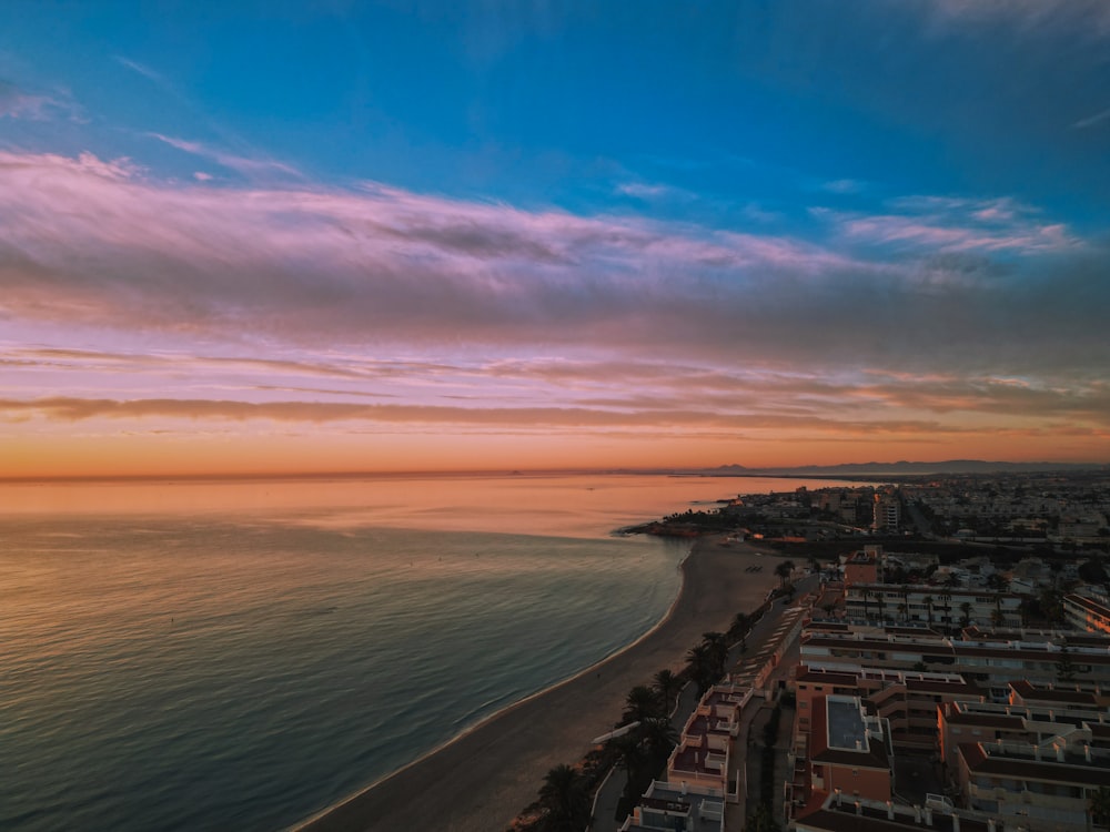 a sunset over a beach with a city in the background