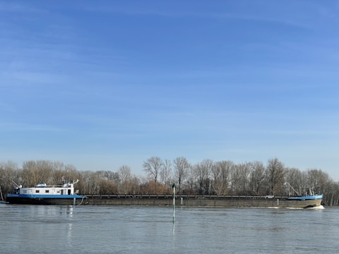 Cargo barge moving along a calm river under a clear sky