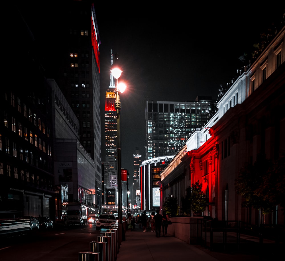 a city street at night with a tall building in the background