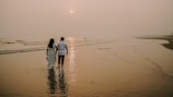 A romantic sunset walk along a beach with a couple holding hands.