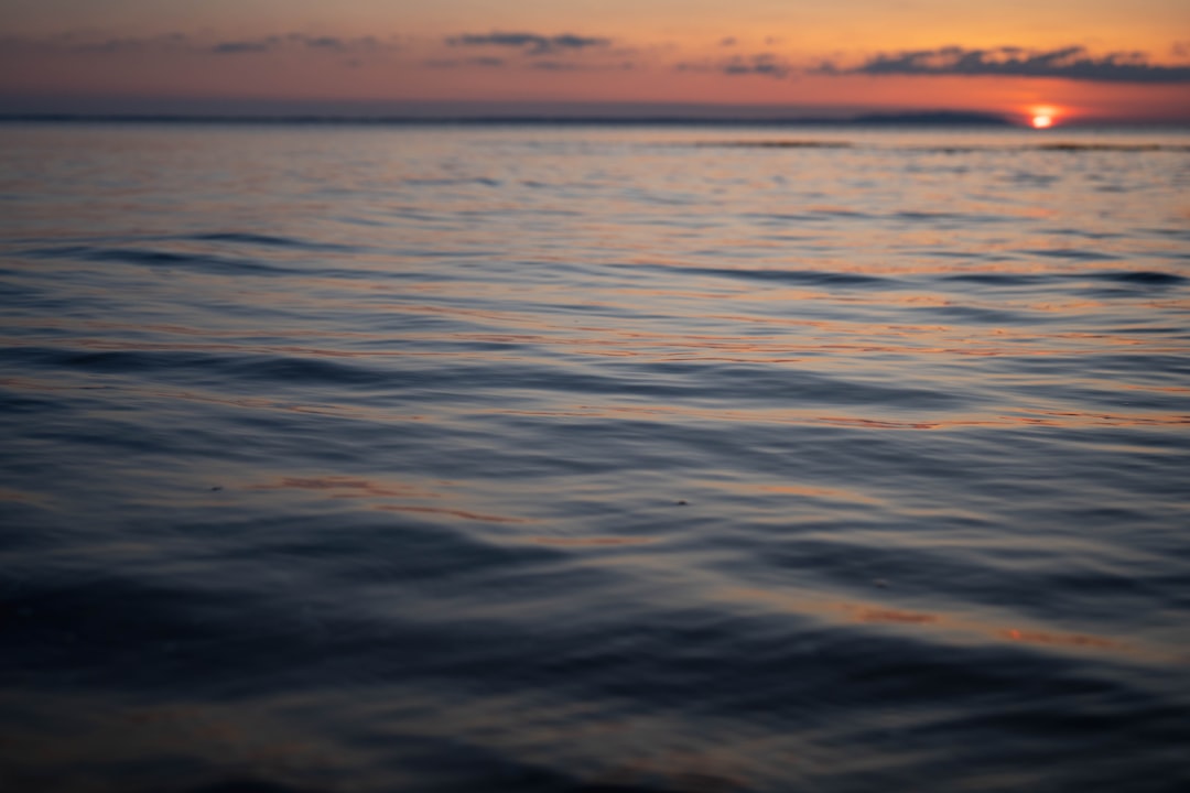 a body of water with a sunset in the background,
