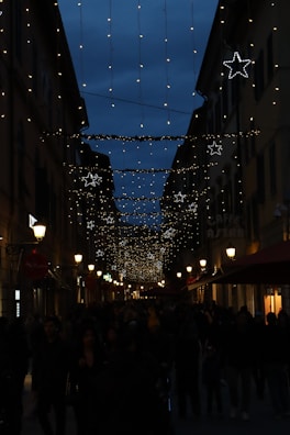 A bustling city street lit by warm golden lights under a deep blue night sky.