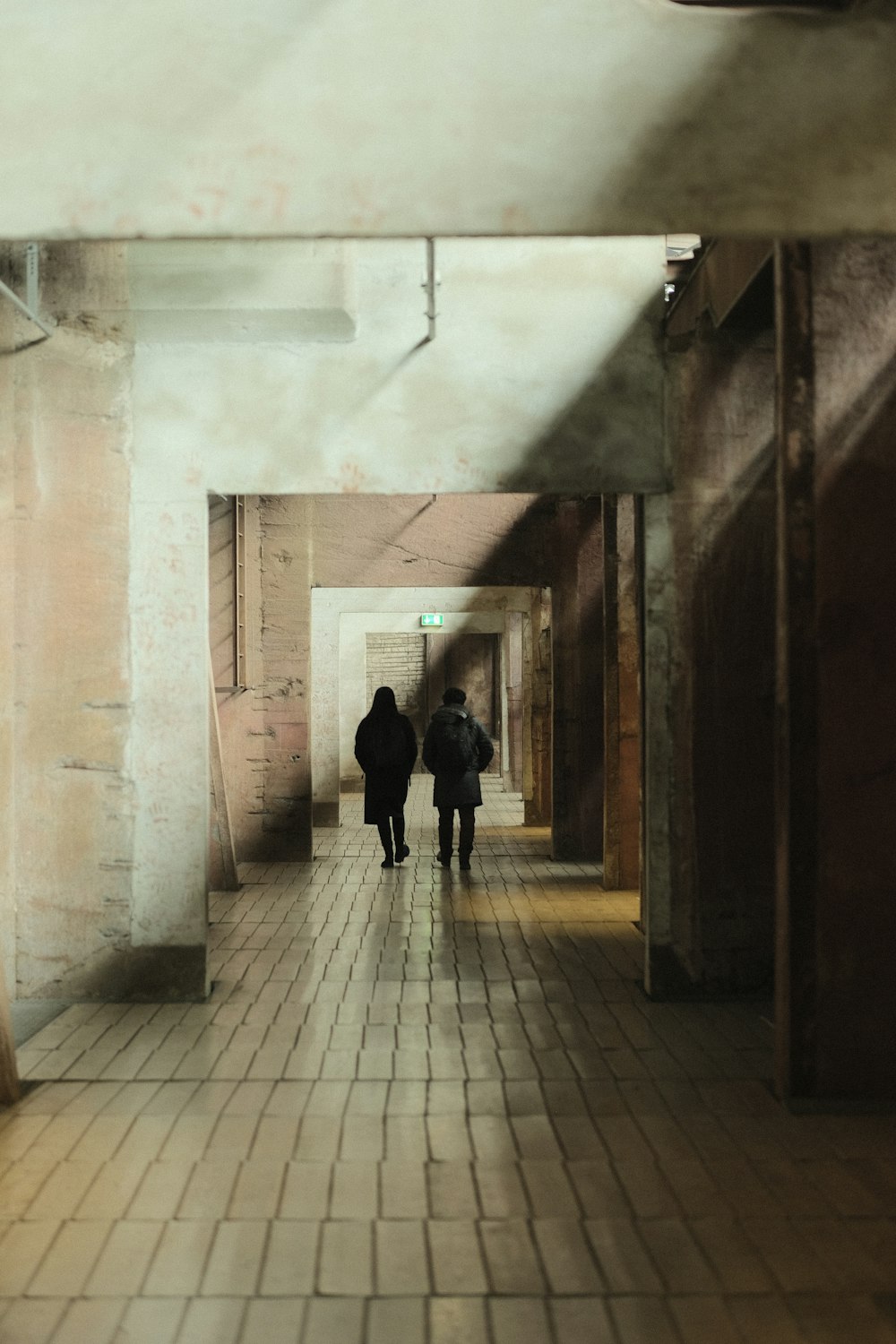 a couple of people walking down a long hallway