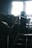A dimly lit industrial setting featuring metal stairs leading up to machinery. A sign with German text is visible, partially obscured by shadows. The background shows diffused light entering through a window.