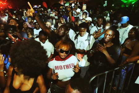 A lively crowd dancing with wireless headphones under colorful street lights at night.