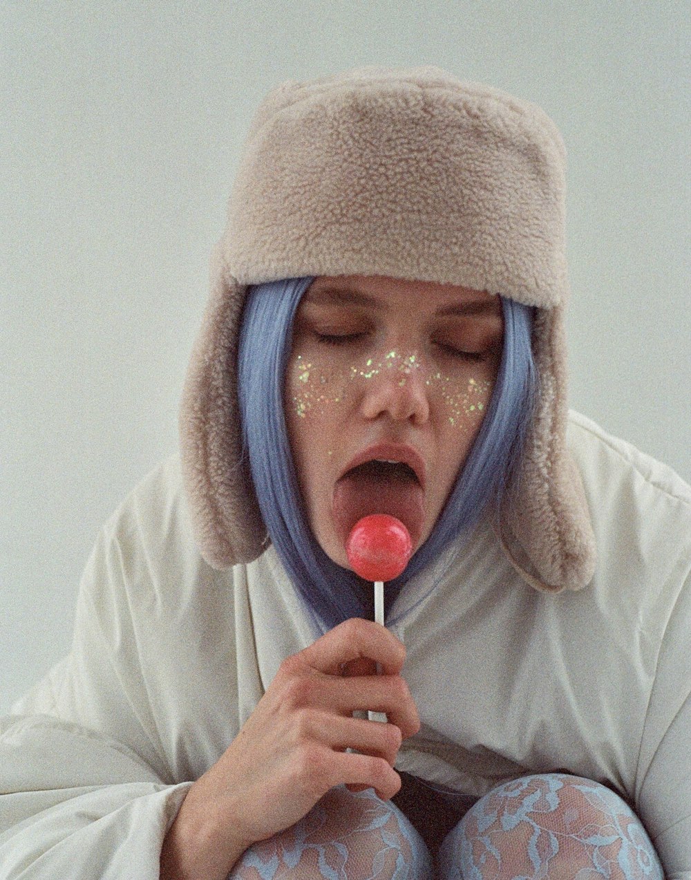 Una donna con i capelli blu tiene in mano un lecca-lecca