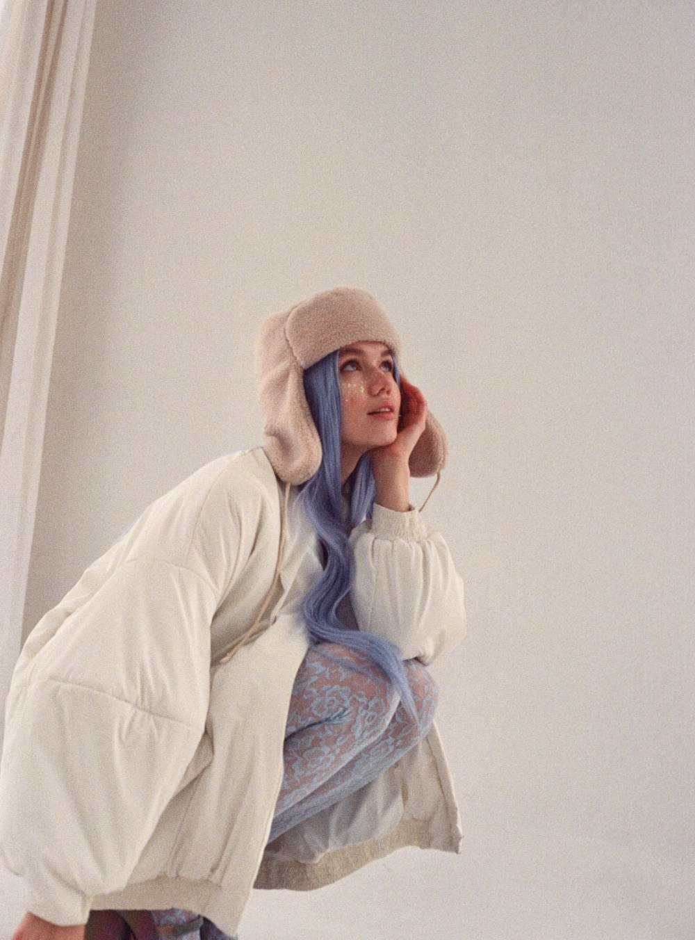 une femme aux cheveux bleus vêtue d’un manteau blanc