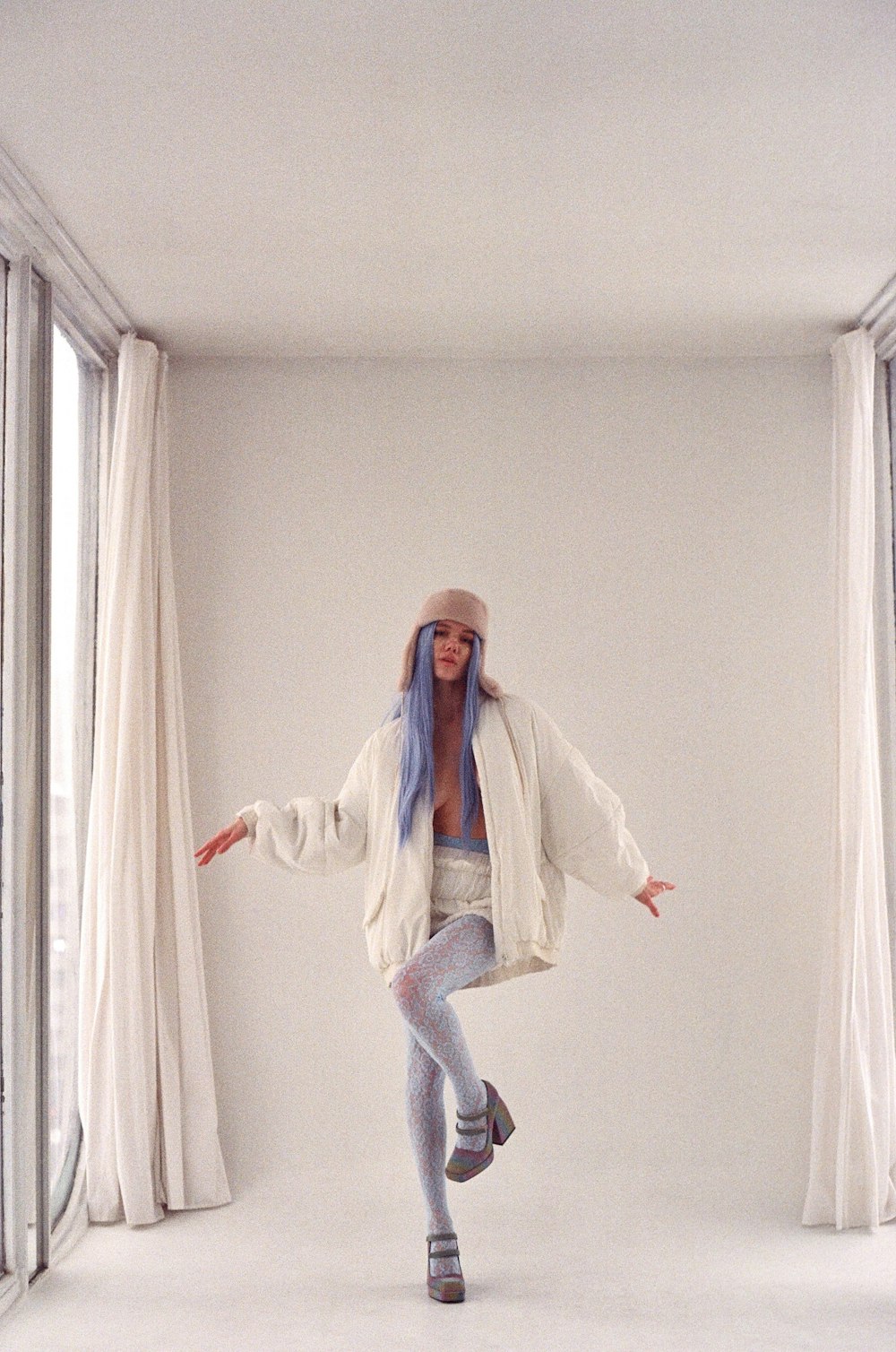 a woman is dancing in a white room