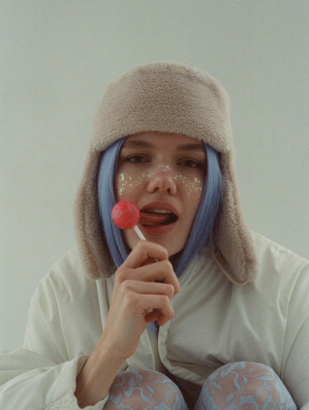 a woman with blue hair is holding a lollipop