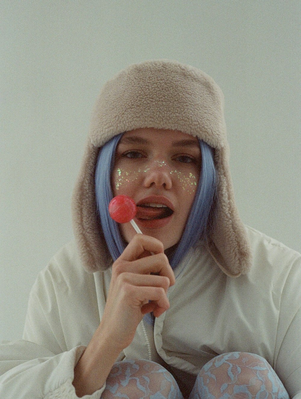 Una donna con i capelli blu tiene in mano un lecca-lecca