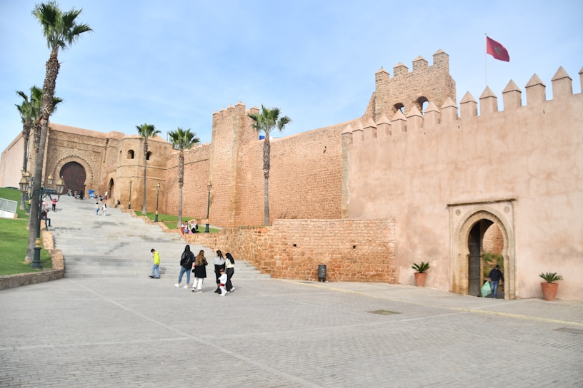 a group of people walking down a street next to a castle