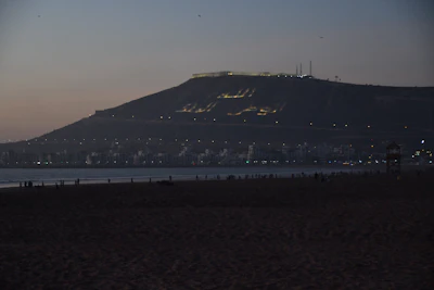 Agadir beach at dusk, under the Kasbah hill and its illuminated inscription