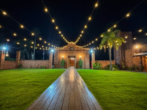 A charming rustic courtyard at sunset with string lights glowing warmly.