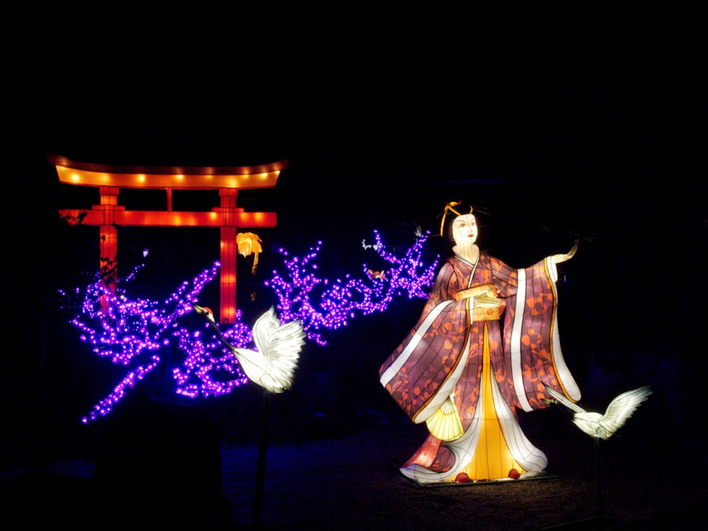 불이 켜진 나무 앞에 서 있는 기모노를 입은 여자