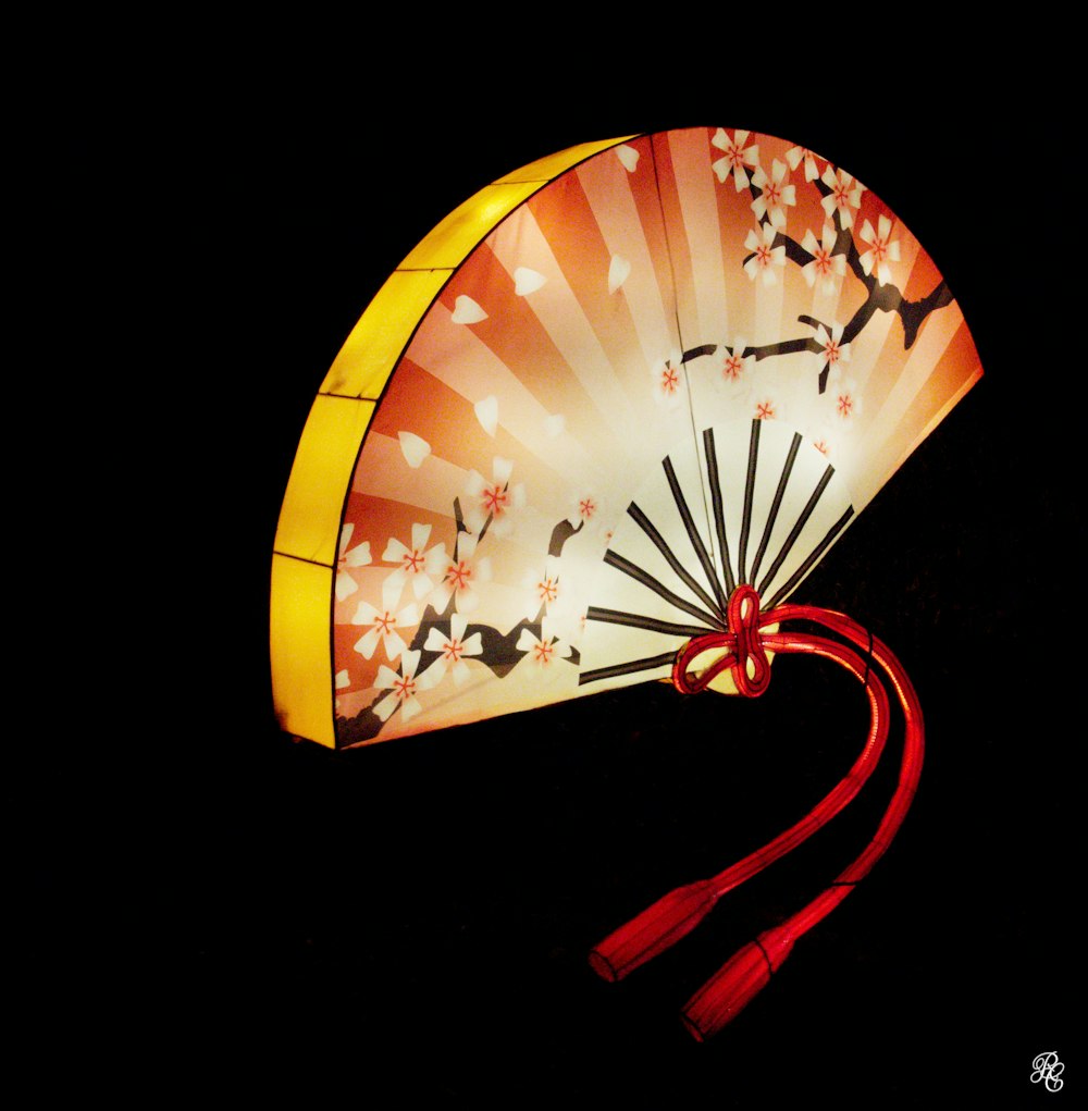a fan with a red ribbon on a black background