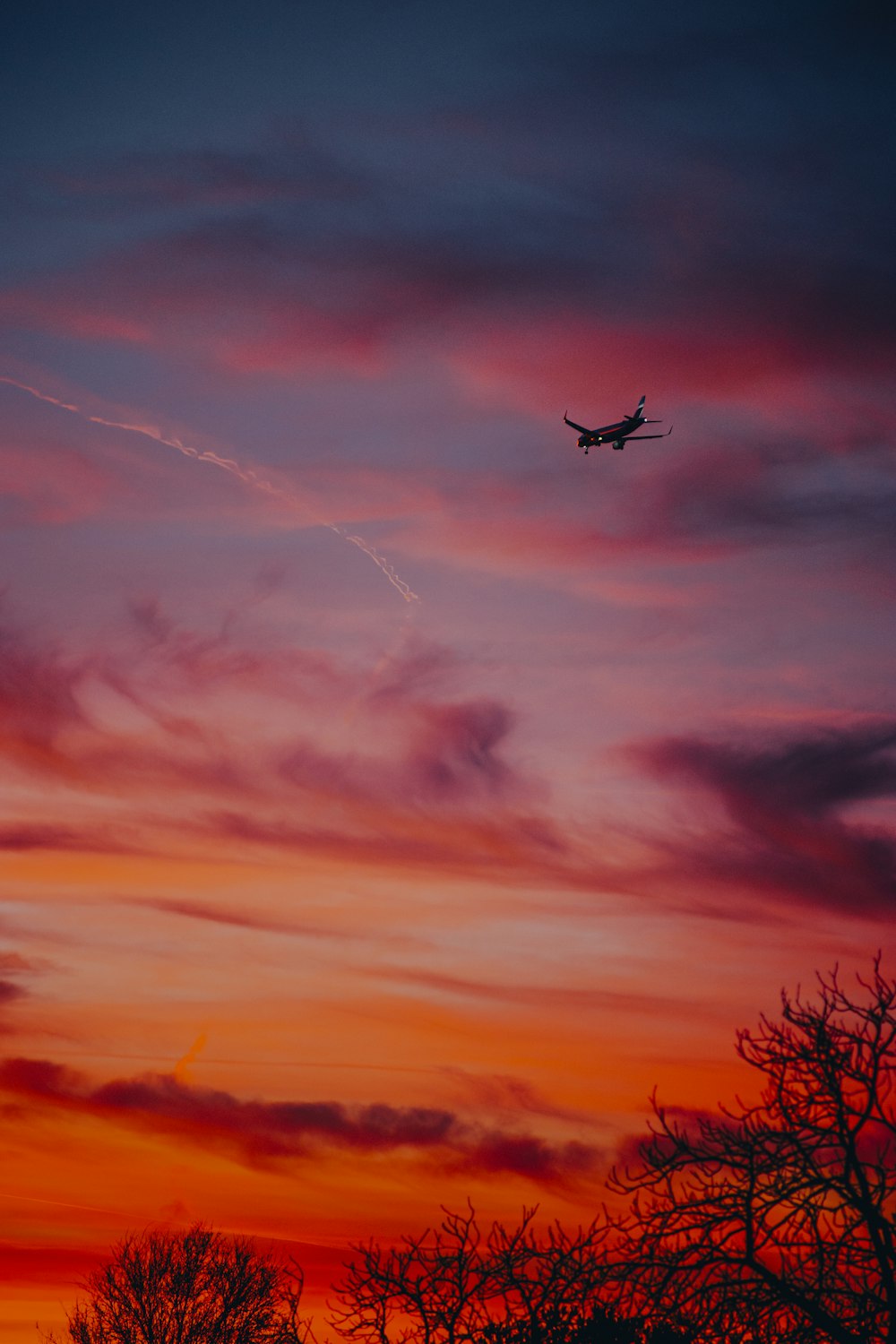 a plane flying in the sky at sunset