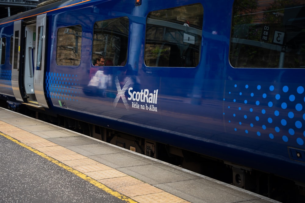 a blue train stopped at a train station