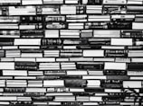 A large collection of books is stacked tightly, covering the entire space from edge to edge. The spines of the books display a variety of titles, some of which include technical and scientific themes. The arrangement appears somewhat chaotic, yet organized in a way that maximizes space.