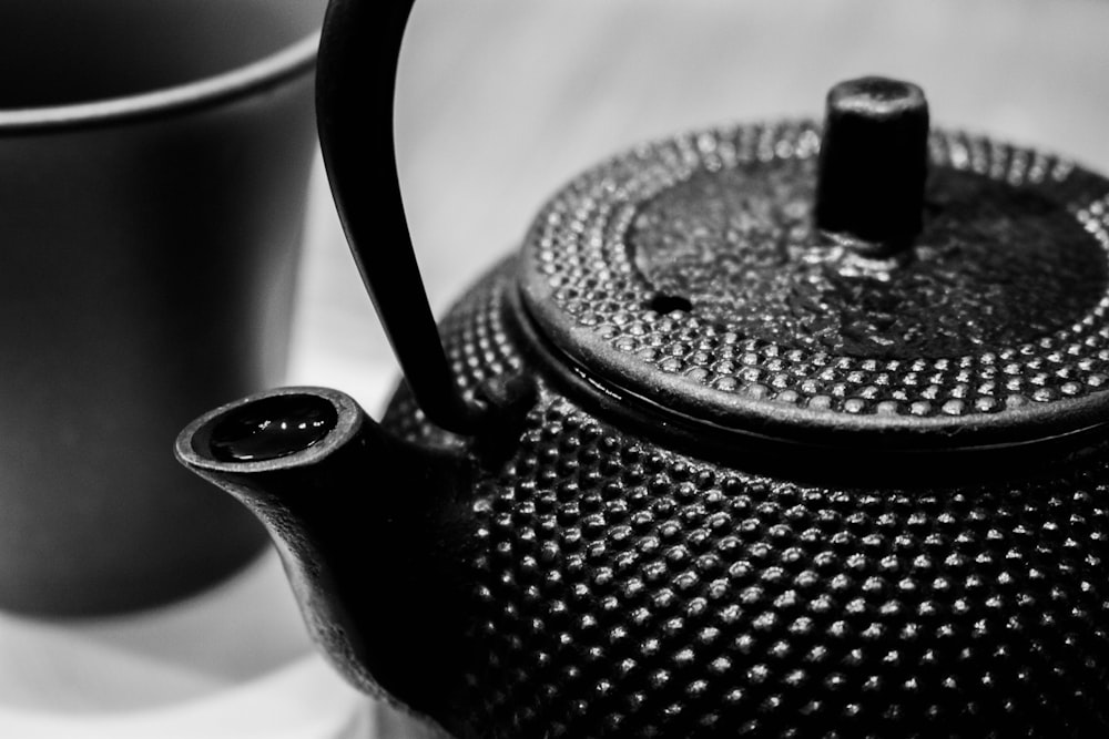a black teapot and two cups on a table