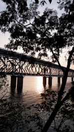 Aerial shot of a large steel bridge under construction over a river at sunset.