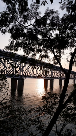 Engineer inspecting a large steel bridge structure at sunset.