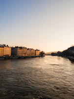 Golden hour view of Alcalá’s river with reflections of blue skies and city architecture.