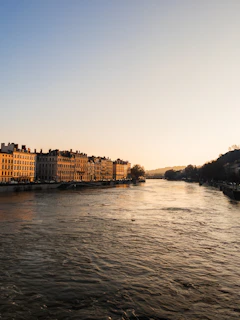 Golden hour view of Alcalá’s river with reflections of blue skies and city architecture.