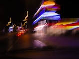 Dynamic shot of a glowing parade of neon lights racing through a nighttime cityscape.
