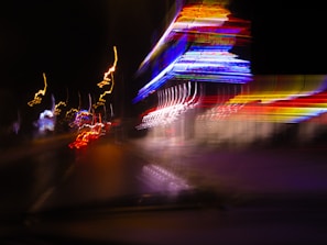 Dynamic shot of a glowing parade of neon lights racing through a nighttime cityscape.