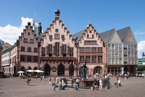 A historic European town square buzzing with life under a bright blue sky