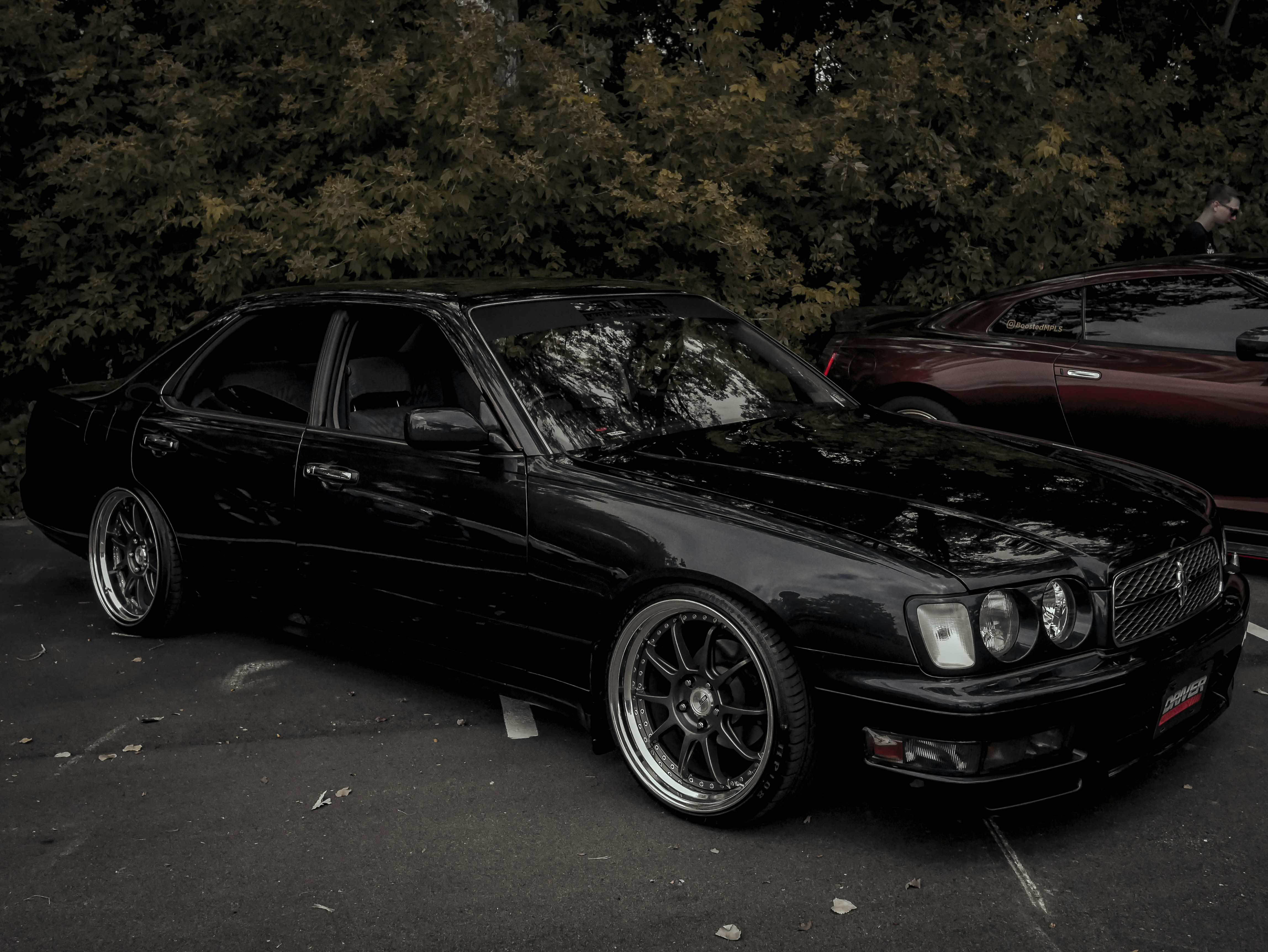 a black car parked in a parking lot next to other cars