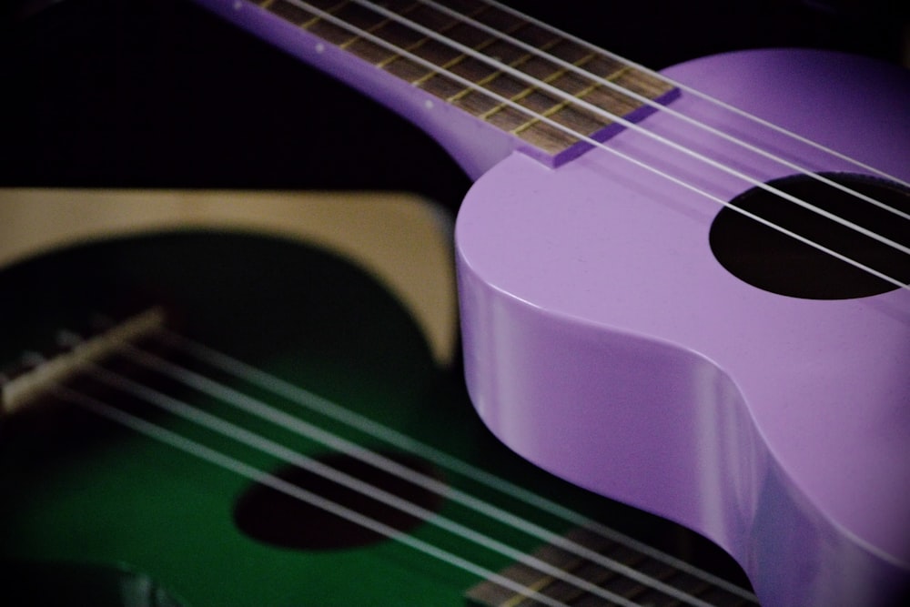 a purple ukulele sitting next to a green ukulele