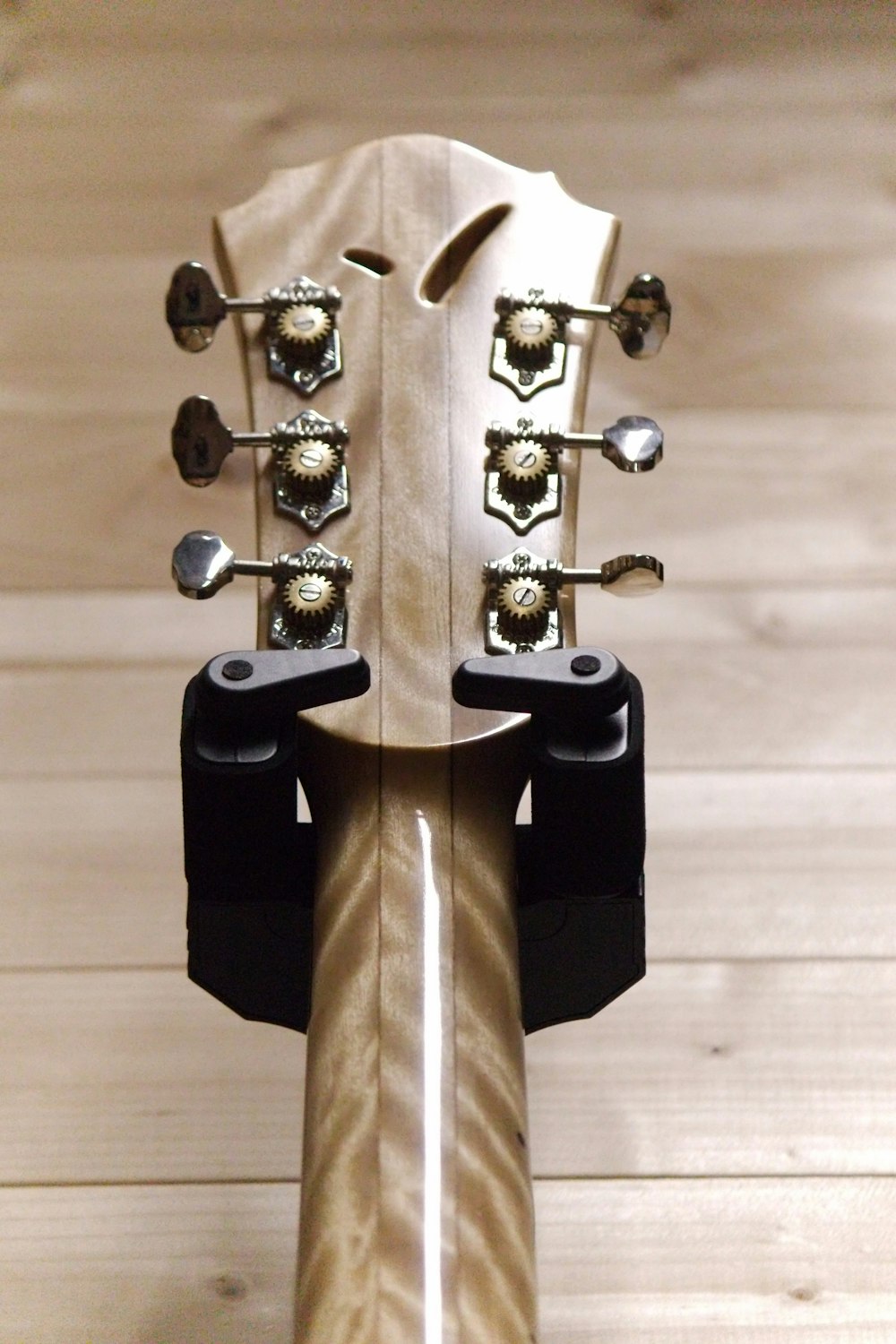 Un primer plano del mástil de una guitarra en un suelo de madera