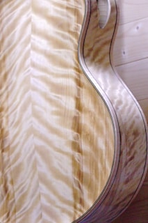 Close-up of a handcrafted acoustic guitar with rich wood grain under soft lighting