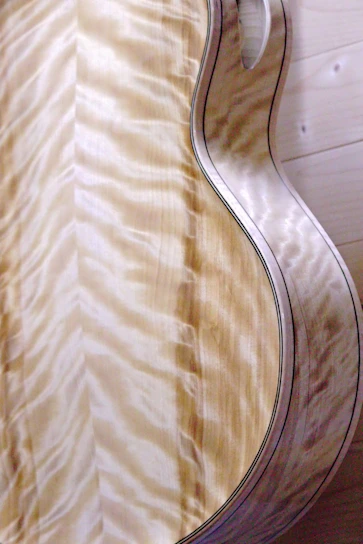 A close-up of a handcrafted wooden acoustic guitar with rich grain patterns and warm lighting.