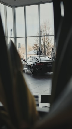 Smartly dressed sales advisor standing confidently in front of a sleek modern car showroom.