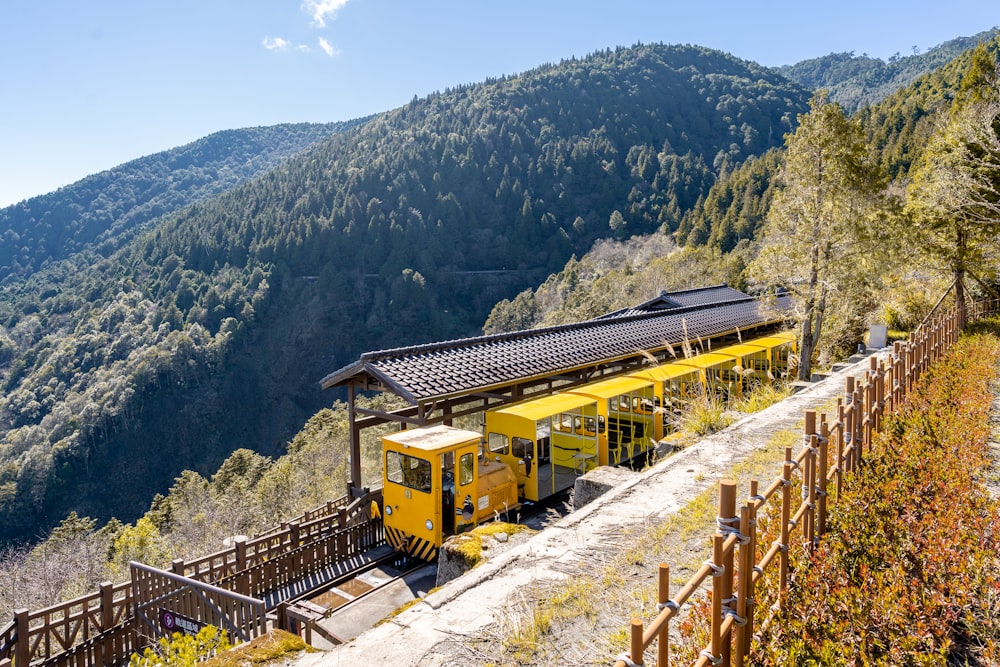 a yellow train traveling down train tracks next to a forest