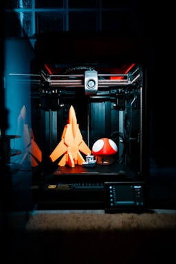 A 3D printer with 'AZ' prominently displayed on the colorful print bed, mid-print of a detailed cosplay prop.
