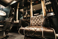 A barber chair in chrome and dark leather under a hanging lamp