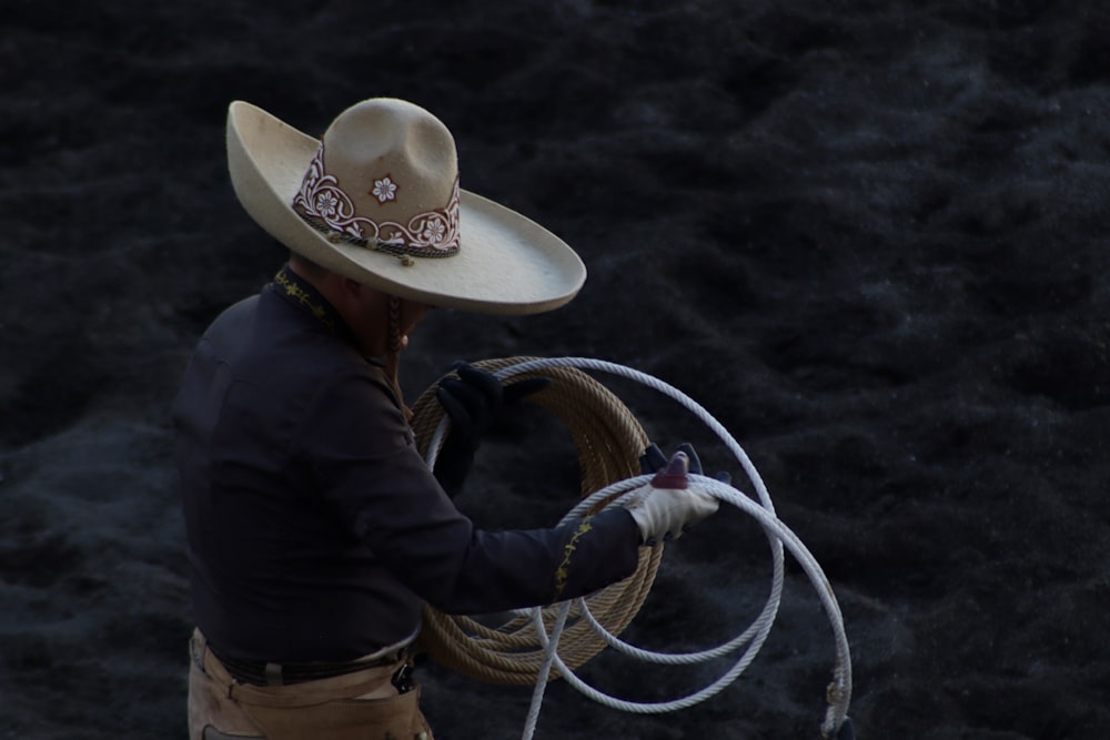 a man in a cowboy hat holding a rope