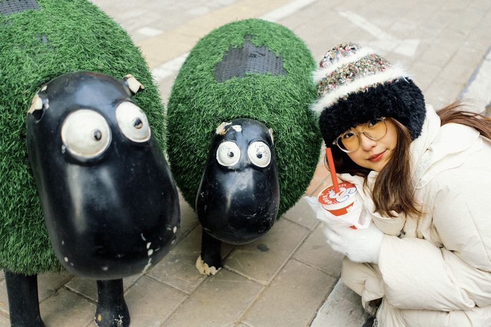 a woman sitting next to three fake sheep