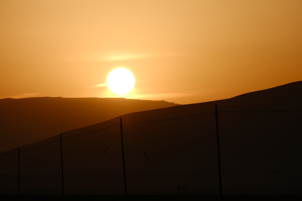 the sun is setting behind a fence in the desert