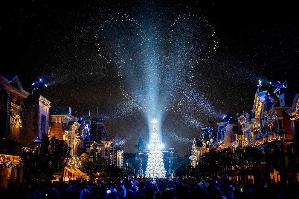 a christmas tree is lit up in the middle of a street