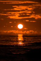 Classic California sunset with vibrant orange sky reflected on calm ocean waters.