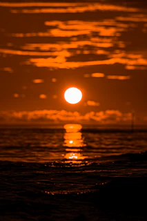 Classic California sunset with vibrant orange sky reflected on calm ocean waters.