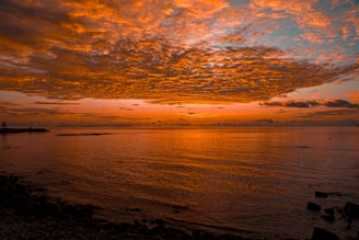 Sunset view from Hotel Seagull's seaside restaurant terrace with vibrant orange and pink skies reflecting on the water.
