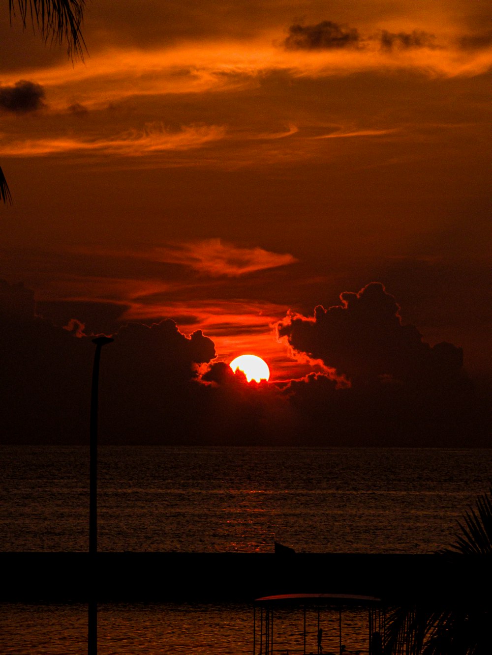 the sun is setting over the ocean with a boat in the foreground