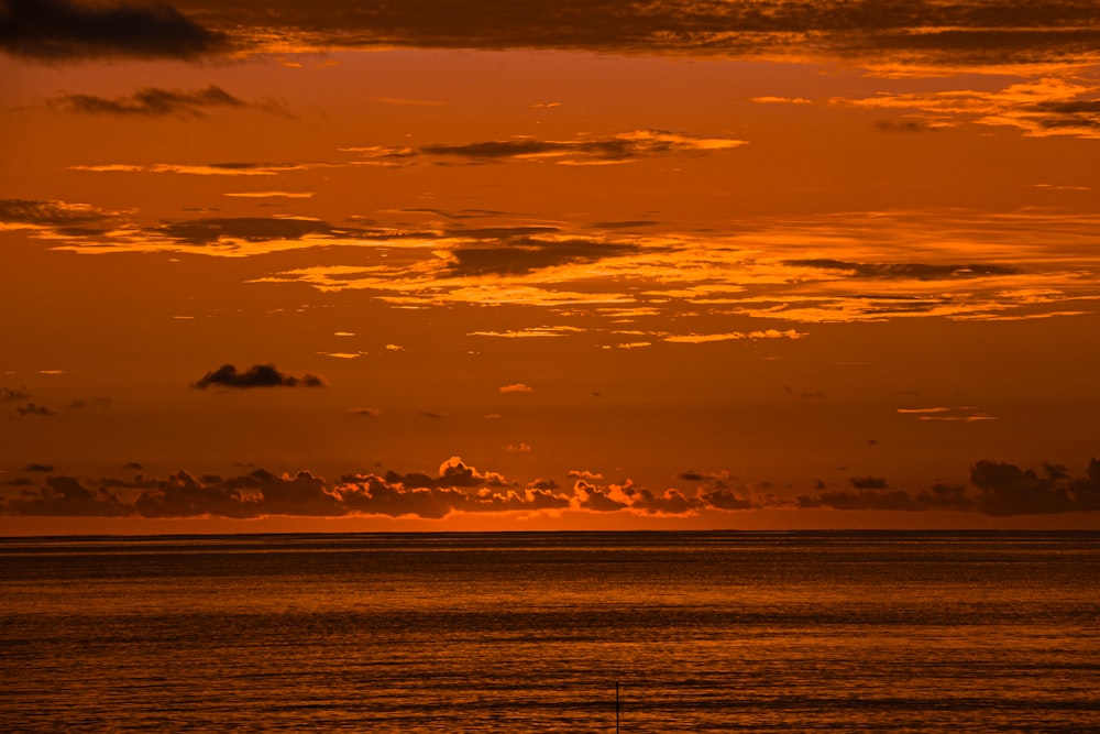 Le soleil se couche sur l’océan avec un voilier au premier plan