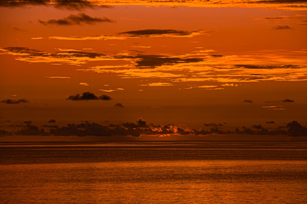 Il sole sta tramontando sull'oceano con le nuvole